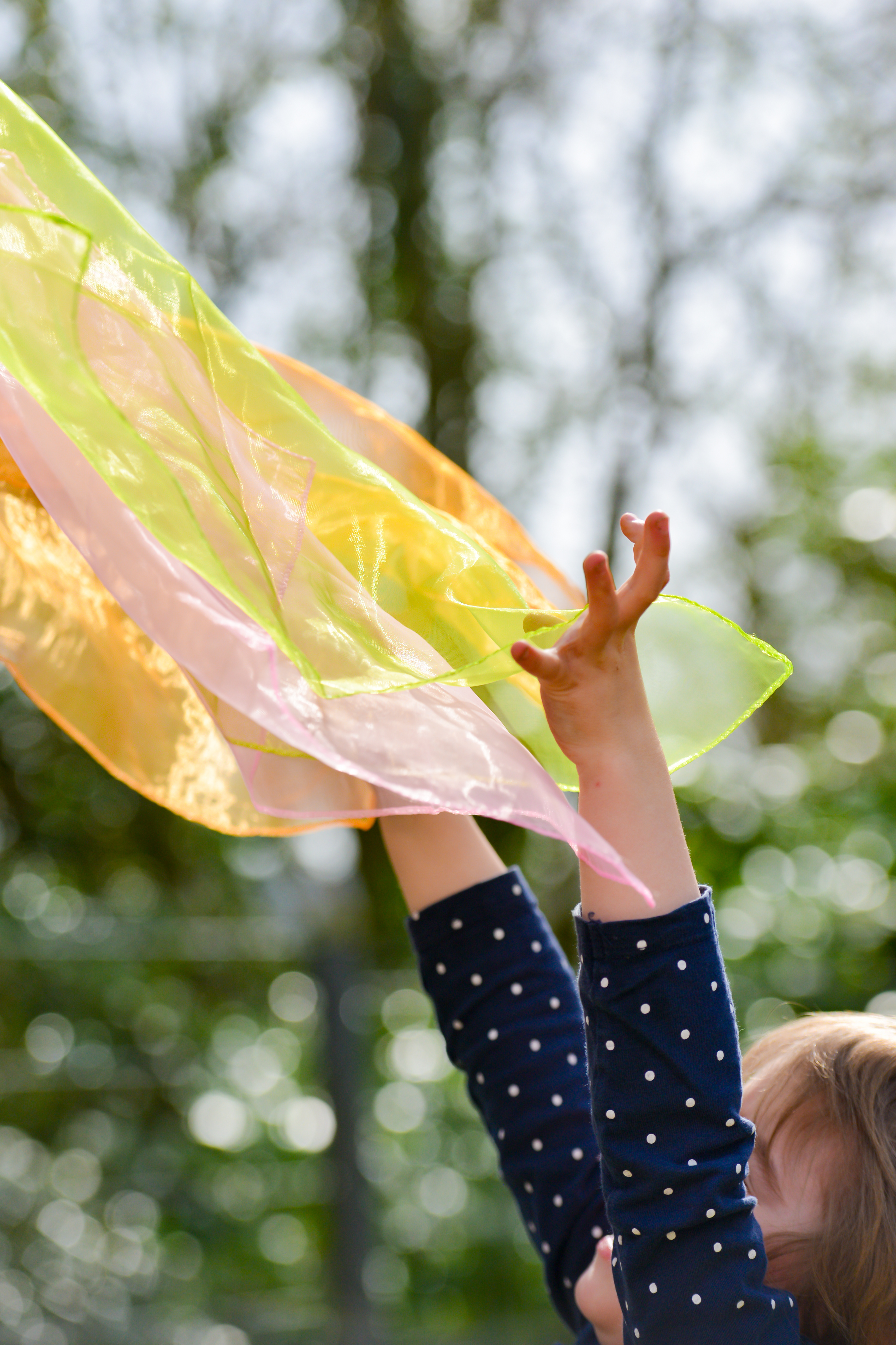 child playing with scarves in wind